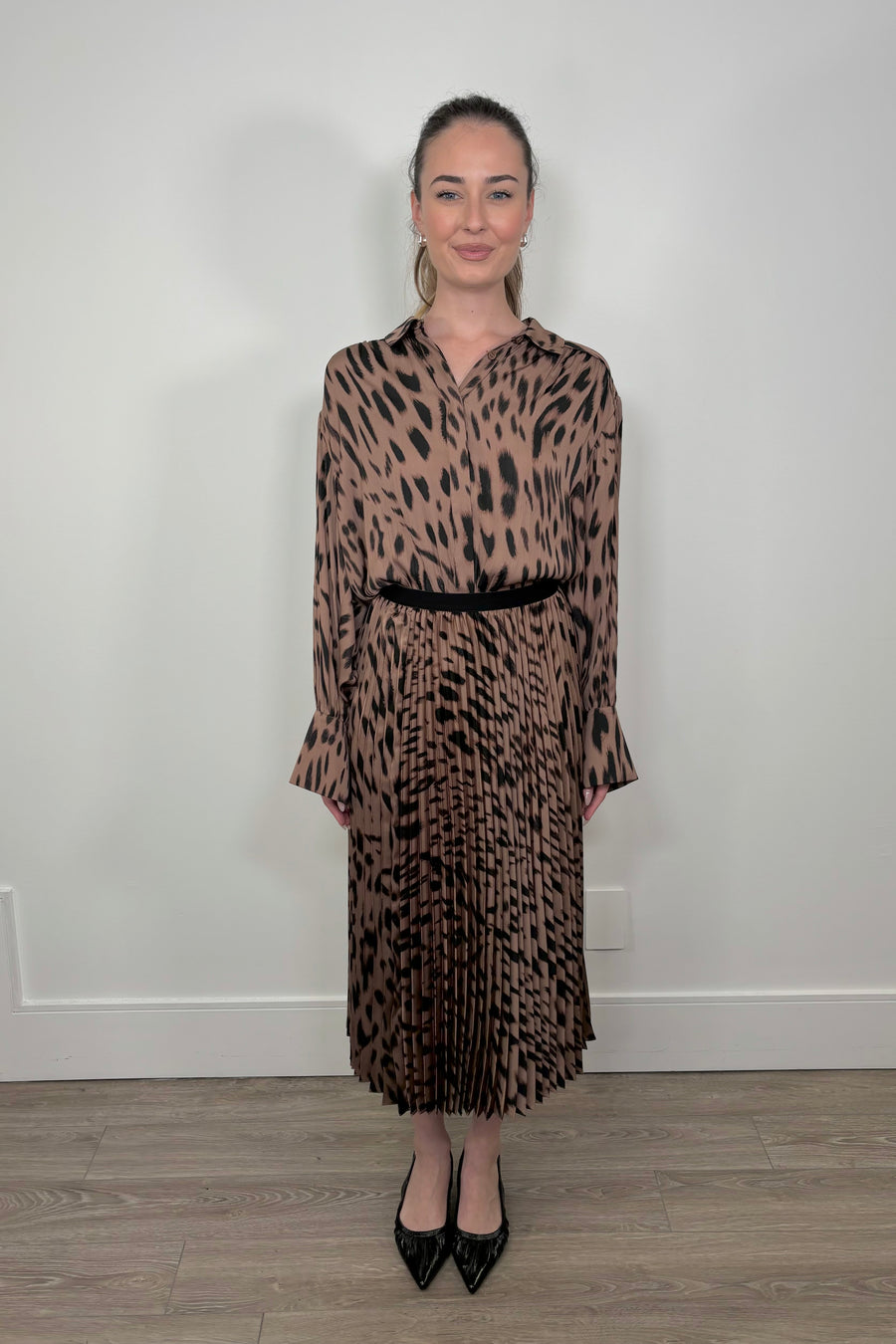 Front view of a woman wearing a leopard printed midi skirt and a matching blouse