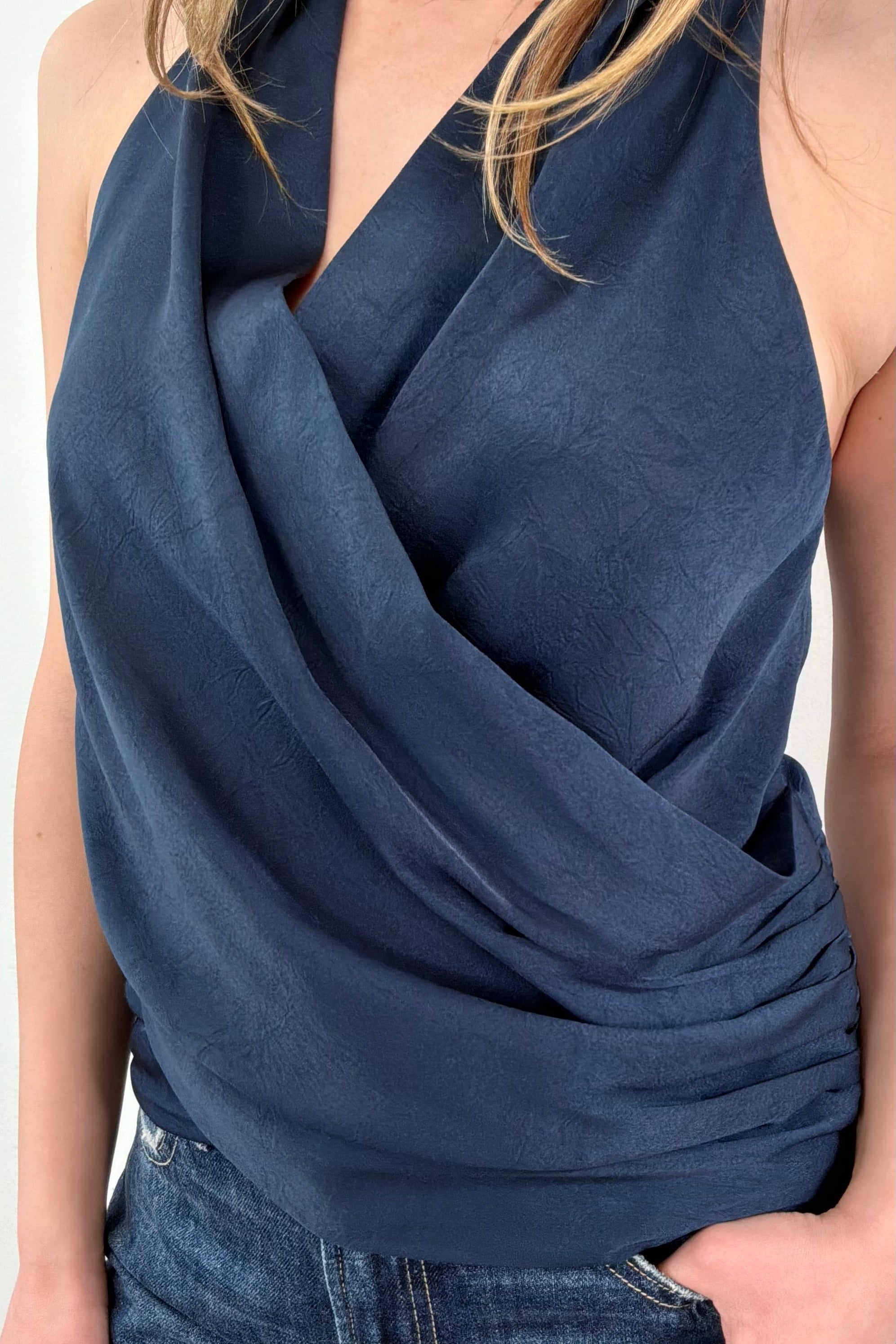 Close up of Woman wearing a satin draped halter top in navy blue