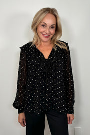 Front view of a woman wearing a sheer polka dot blouse