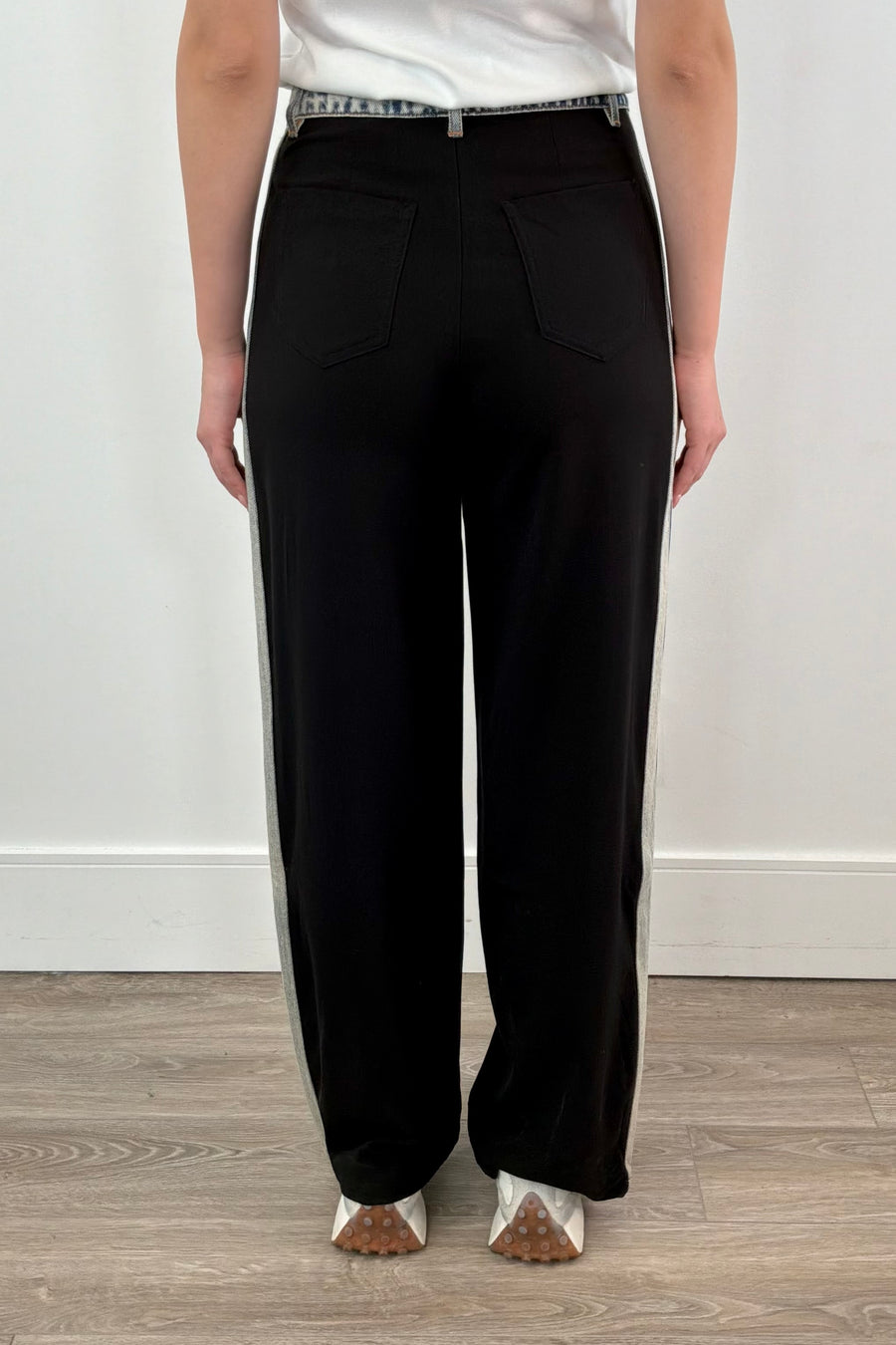 Back view of Woman wearing black dress pants with accents of light indigo denim