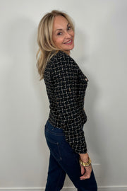 Side view of a woman wearing a navy houndstood patterned blazer with gold hardware