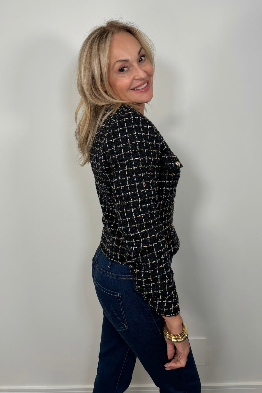 Side view of a woman wearing a navy houndstood patterned blazer with gold hardware