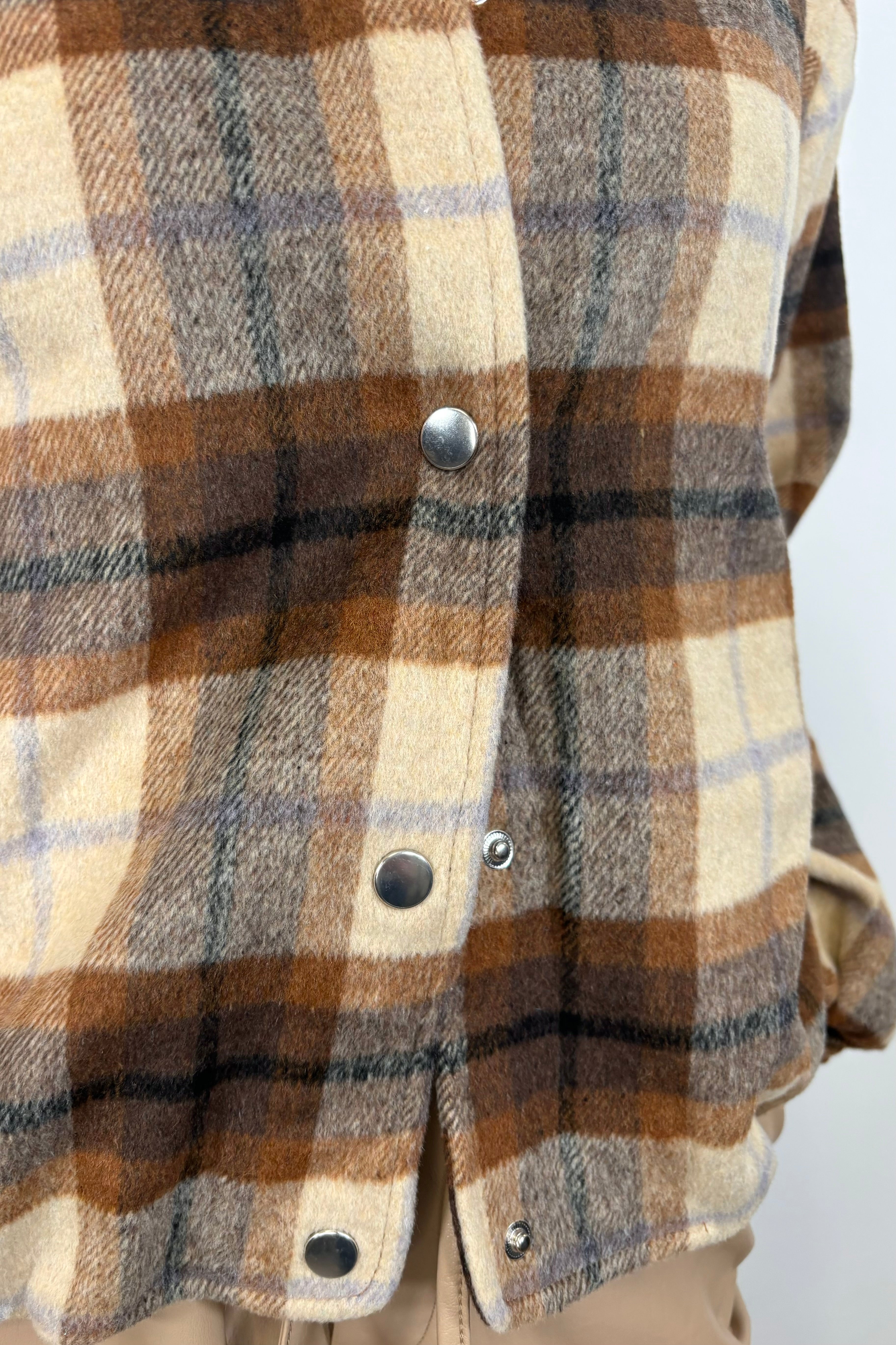 Close-up of a brown plaided bomber jacket with snap buttons