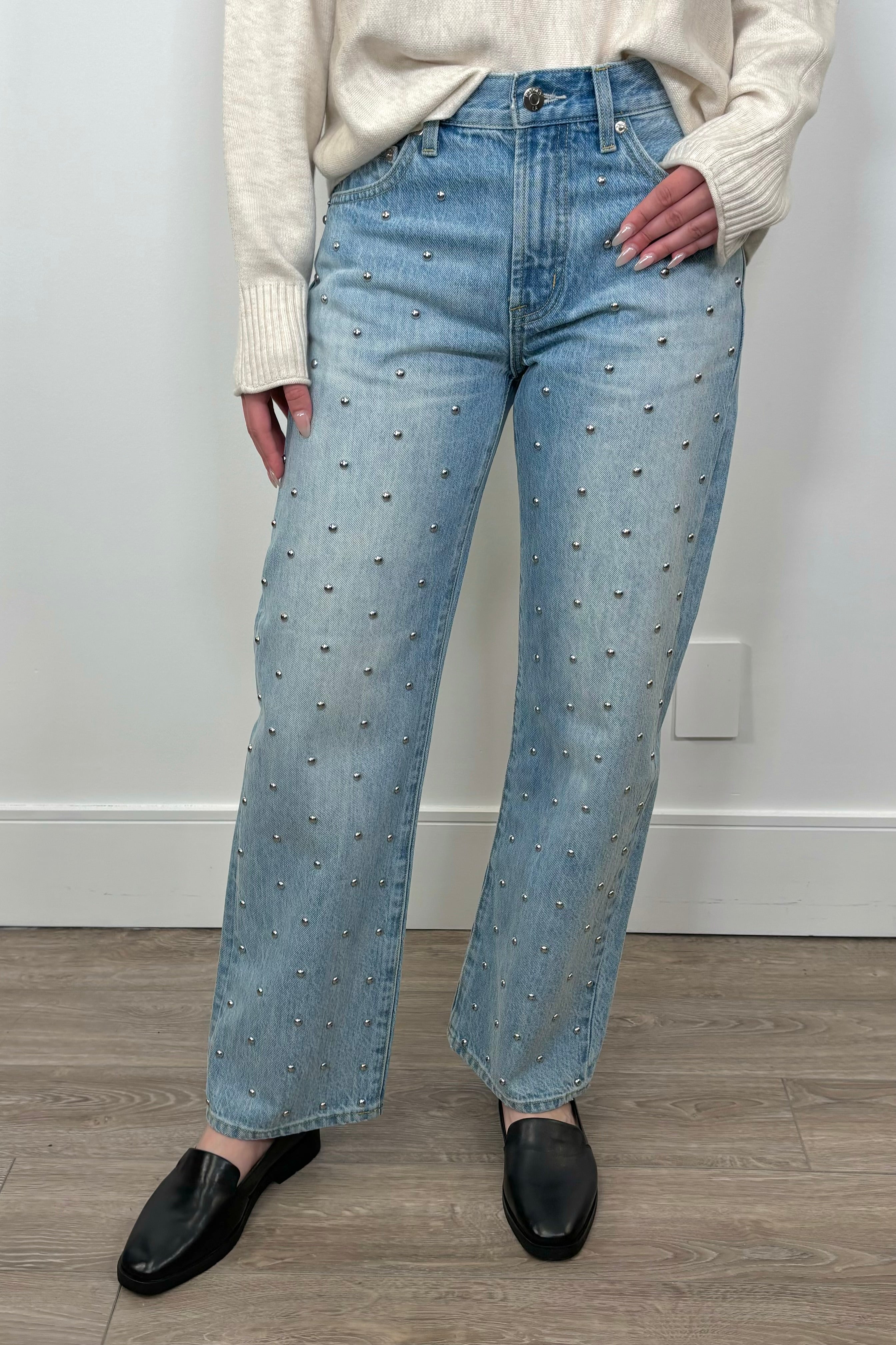 Front view of woman wearing blue denim jeans with silver studs