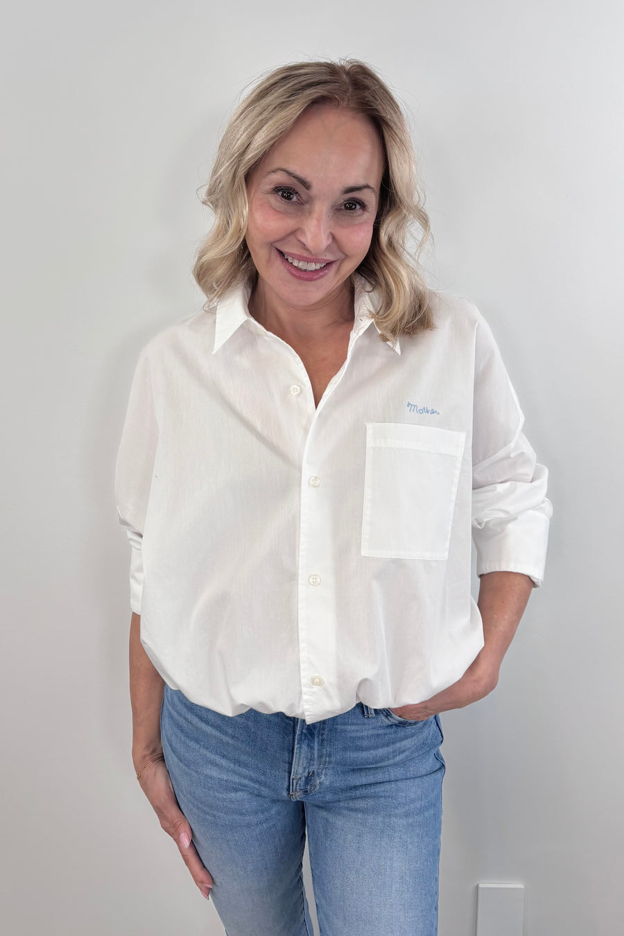 a woman wearing a cropped white button up collared shirt with a side pocket