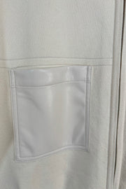 Close-up of the pocket of a cream coloured mix media bomber jacket 