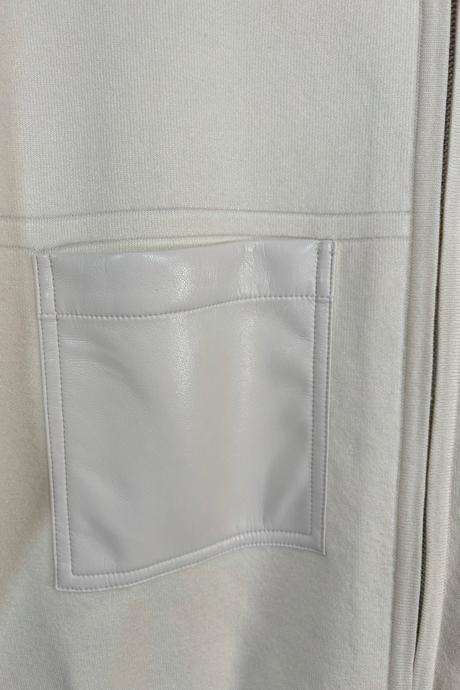 Close-up of the pocket of a cream coloured mix media bomber jacket 
