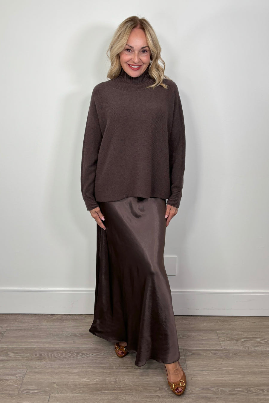 woman wearing a brown slip on satin maxi dress and a brown oversized mock neck sweater 