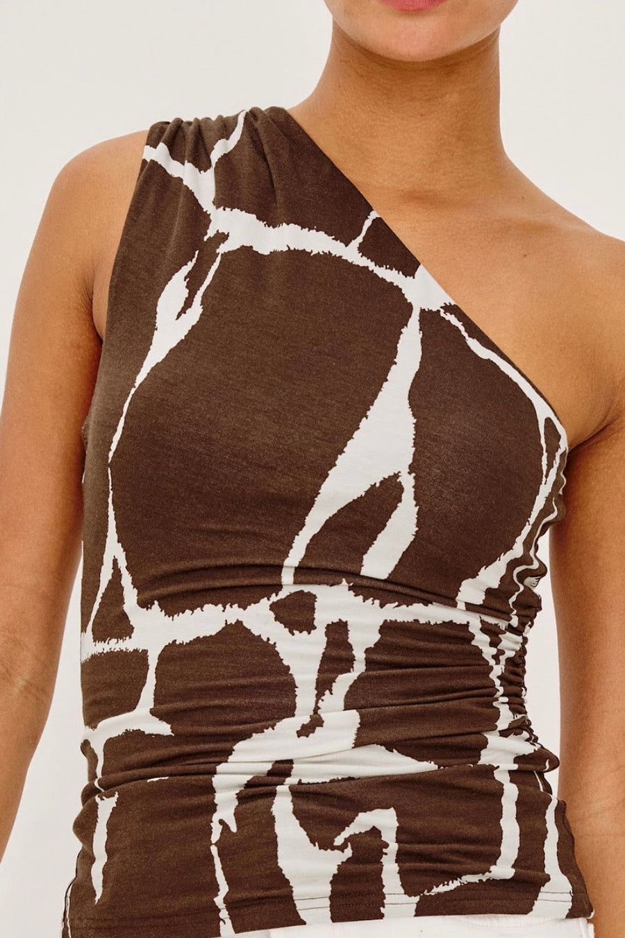 Close up of Woman wearing a brown and white printed off one shoulder top