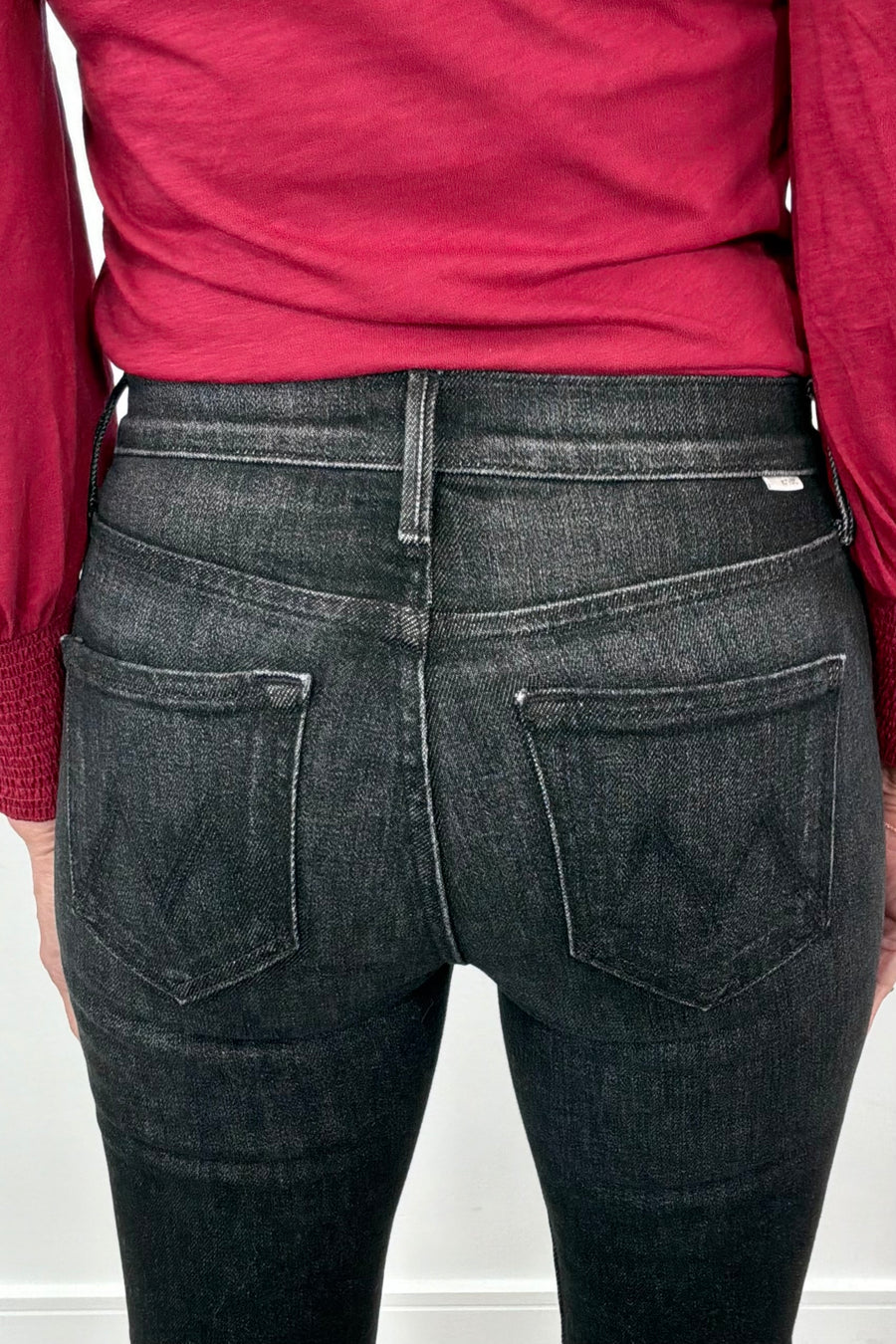 close-up of the back of washed black fitted jeans and a red top