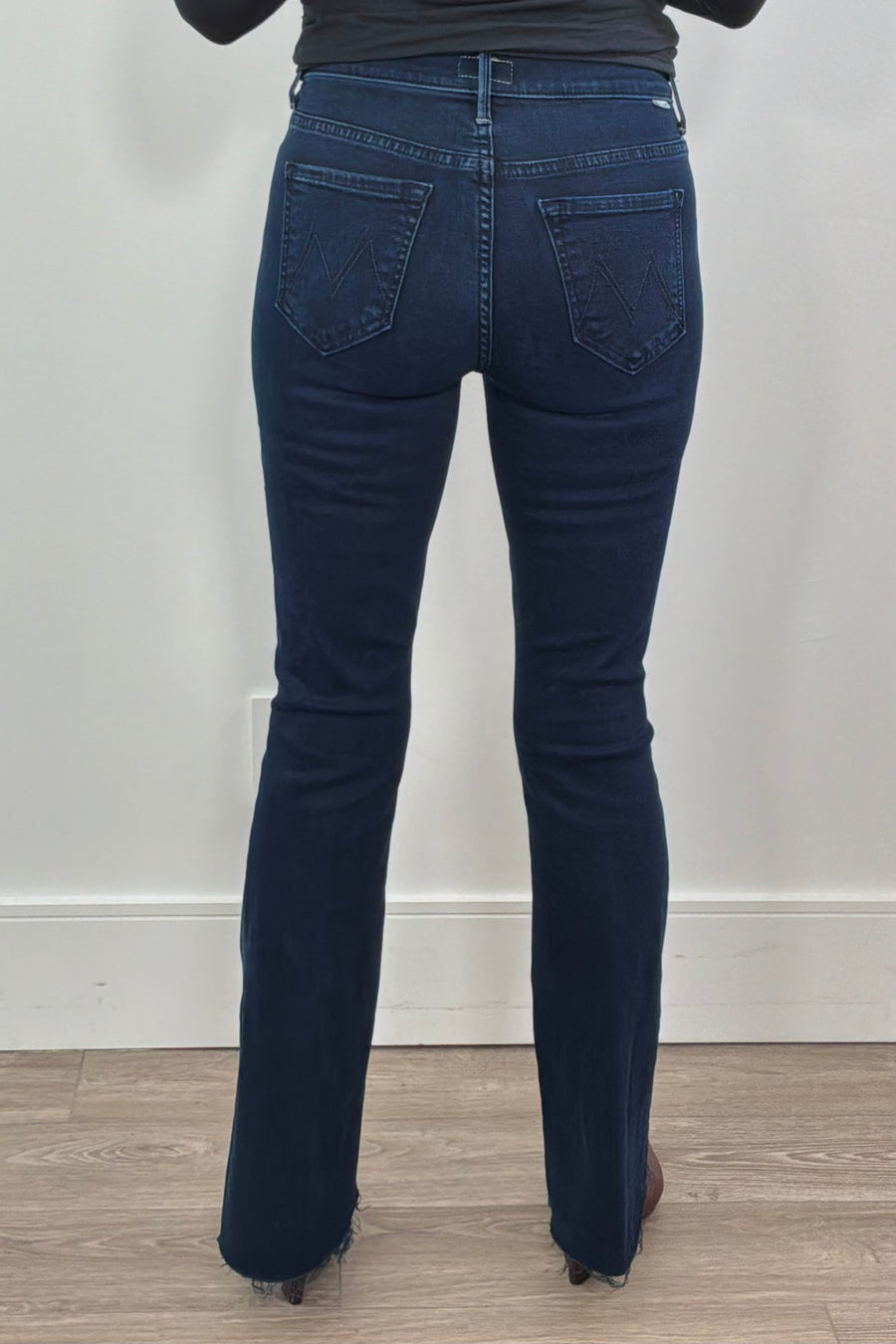 Person wearing frayed dark blue jeans 