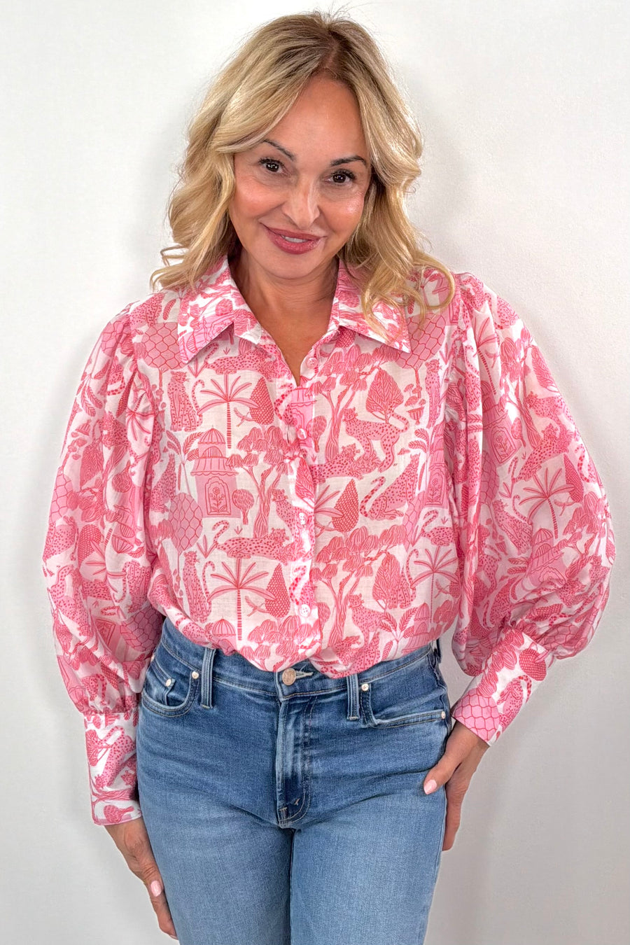Woman wearing pink and white long sleeve blouse with jungle print all over