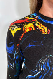 Close-up of a black sweater with colorful abstract patterns on a plain background