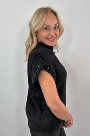 woman wearing a black fuzzy cap sleeve embellished sweater