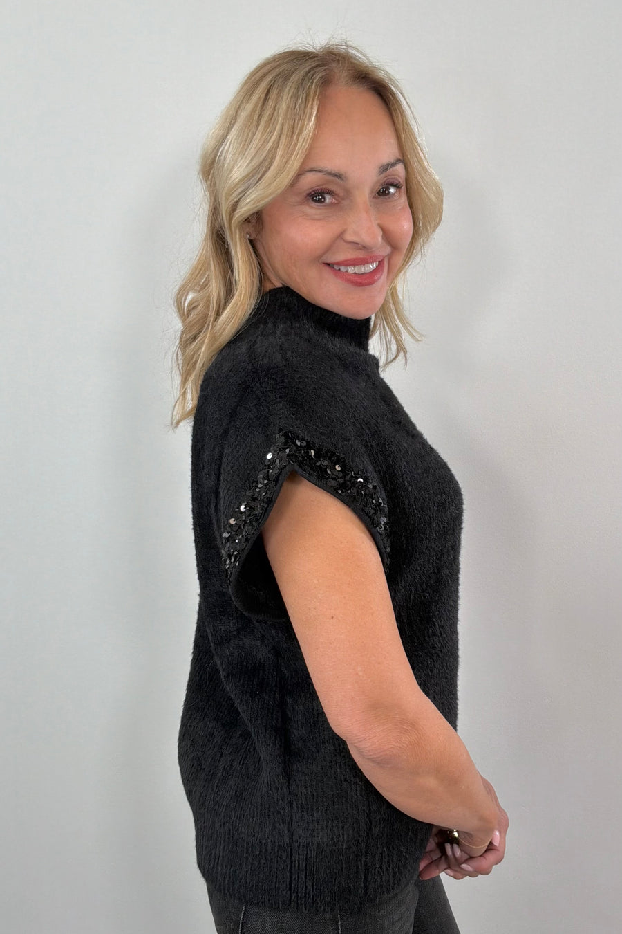 woman wearing a black fuzzy cap sleeve embellished sweater