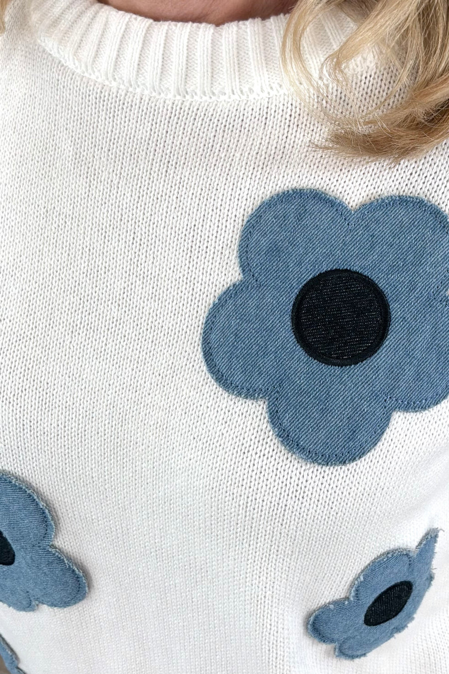 Close up of Woman wearing a while knit follower with denim floral design