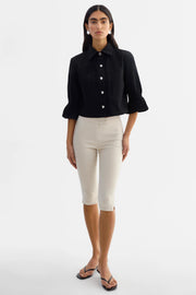 Woman wearing a black jacket with silver buttons and 3/4 sleeves. 