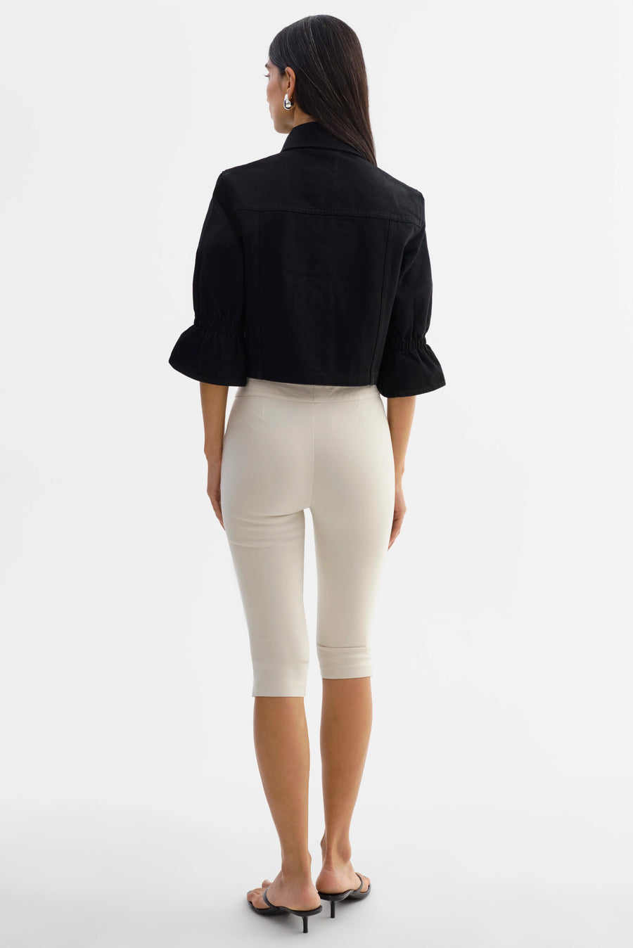 Woman wearing a black jacket with silver buttons and 3/4 sleeves. 