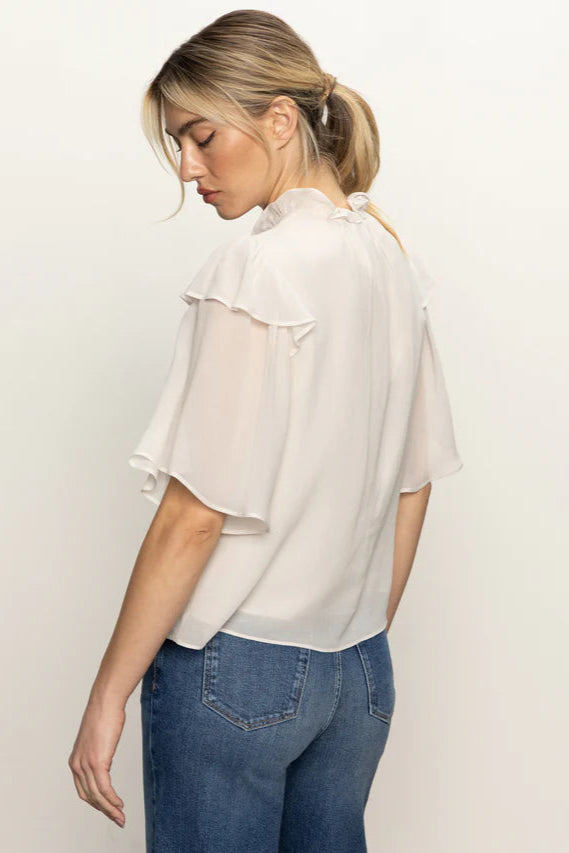 Back view of woman wearing an oat coloured light blouse