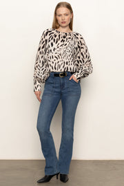 Front full body view of woman wearing a sheer printed blouse with a cami underneath
