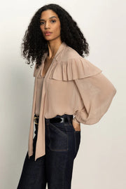 Side view of woman wearing a nude coloured sheer ruffle tie neck blouse