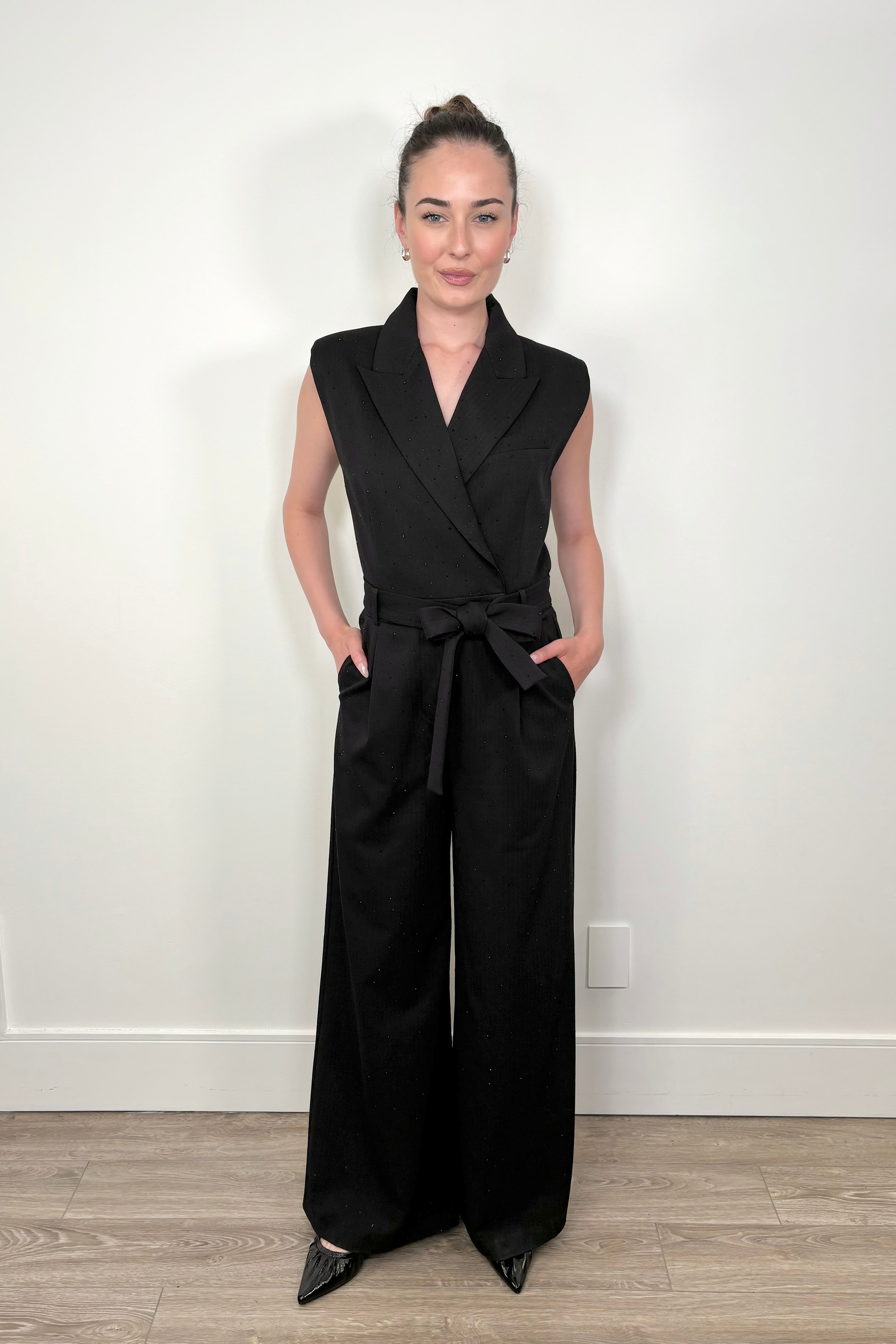 Front view of woman wearing a black pinstriped jumpsuit with sparkle embelishment