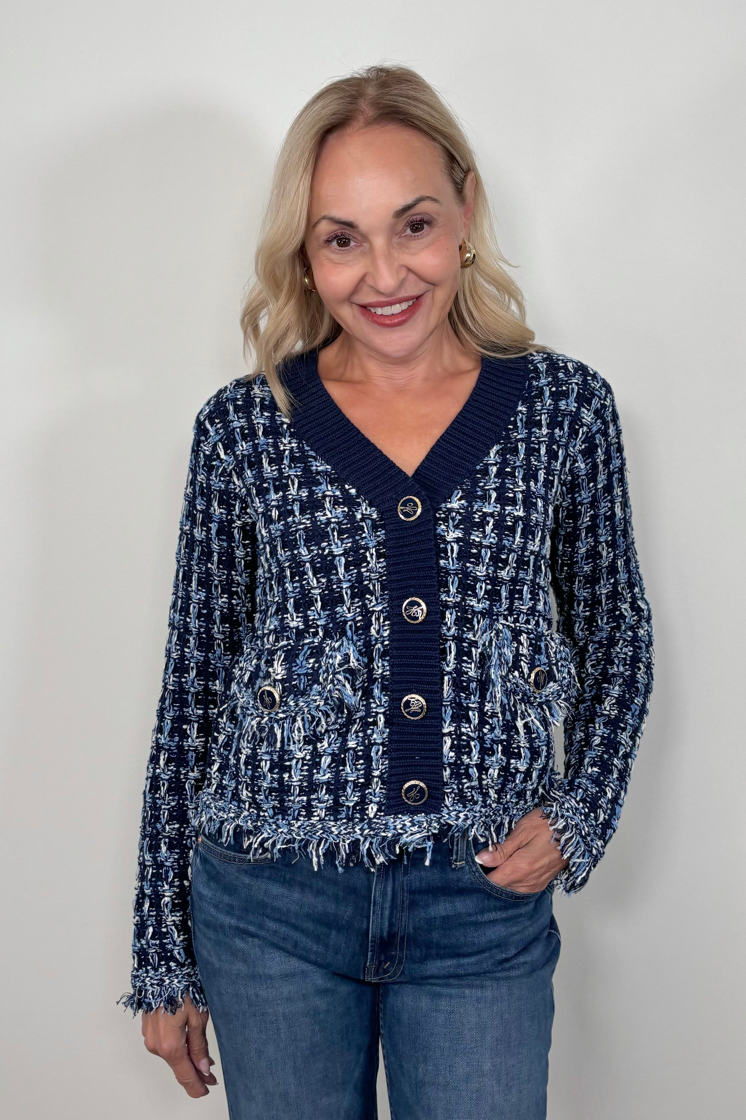 Front view of woman wearing a knit blue jacket with ornamental buttons