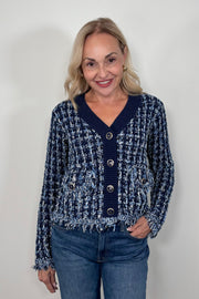 Front view of woman wearing a knit blue jacket with ornamental buttons