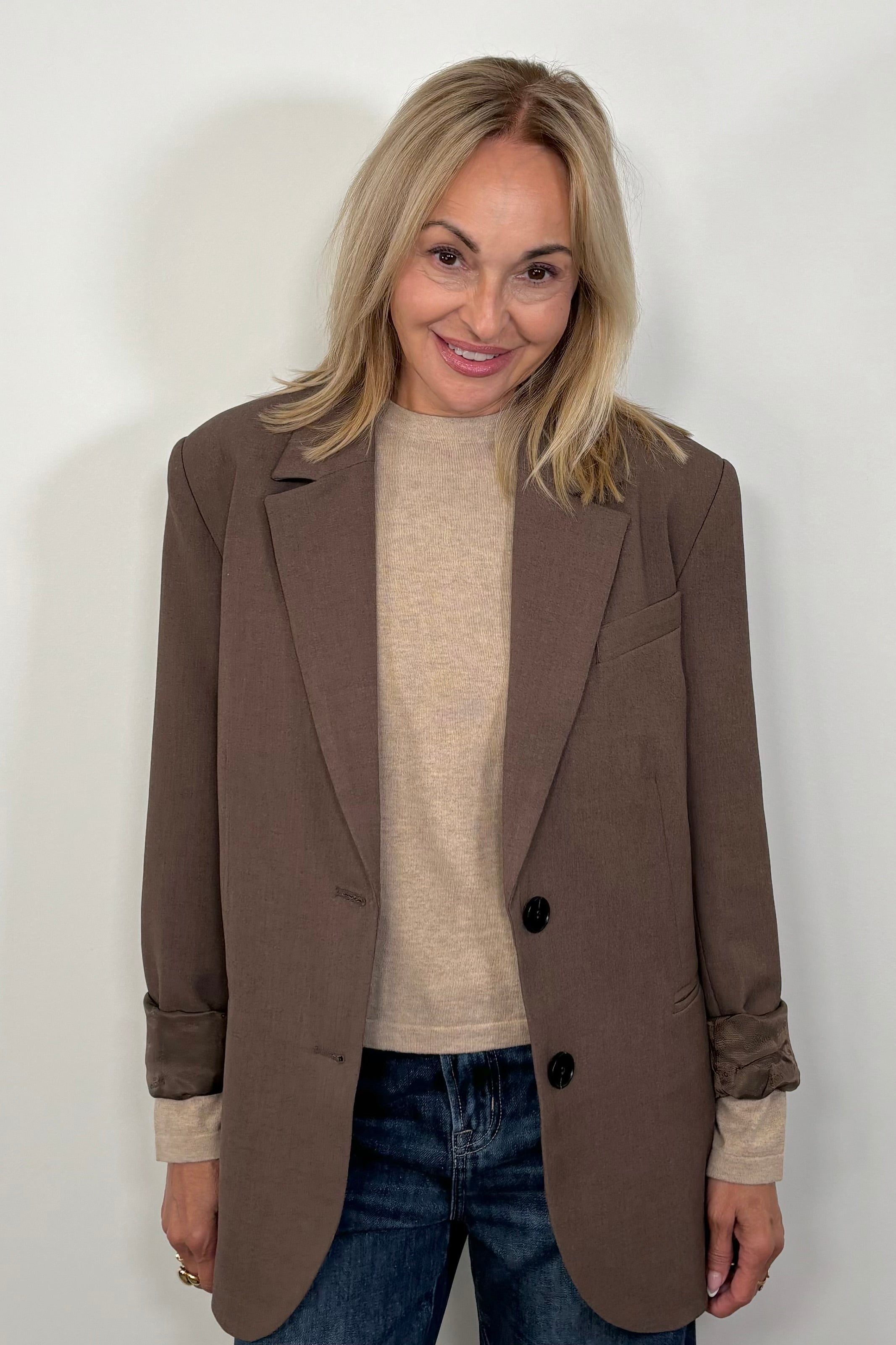 Front view of woman wearing a cool brown blazer over a beige top