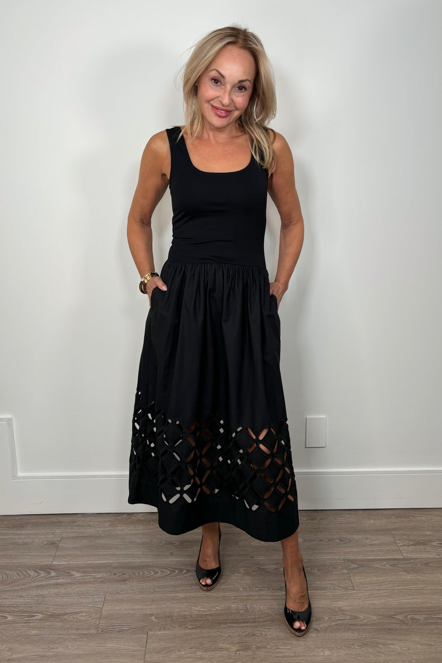 Front view of woman wearing a black cotton dress with cut outs in the bottom
