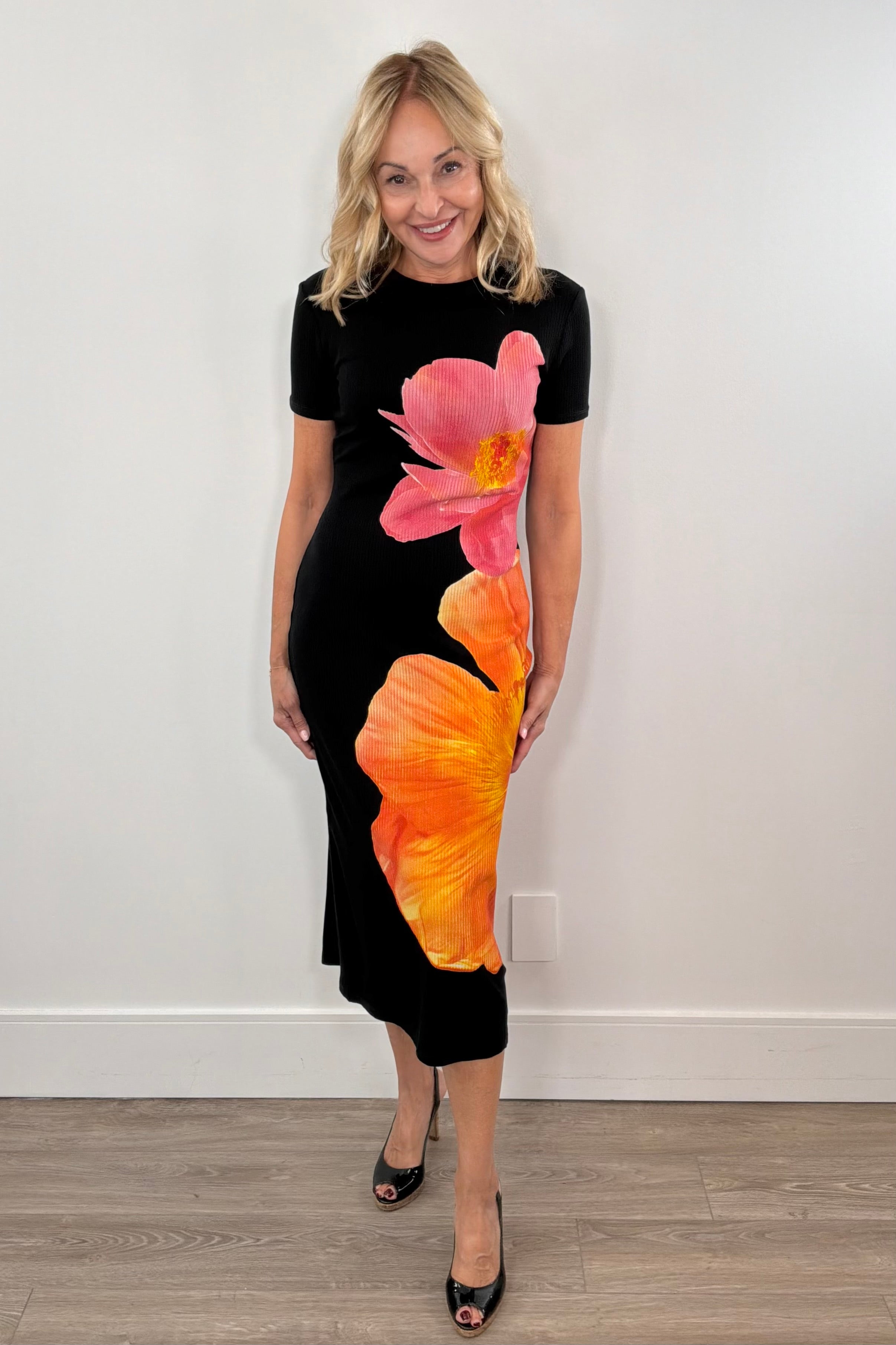 woman wearing a midi black dress with a two flower print