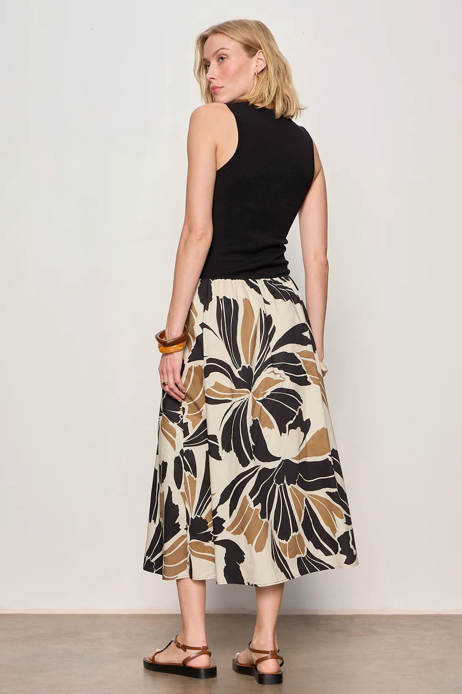 Woman wearing a black midi dress with lotus pattern detail 