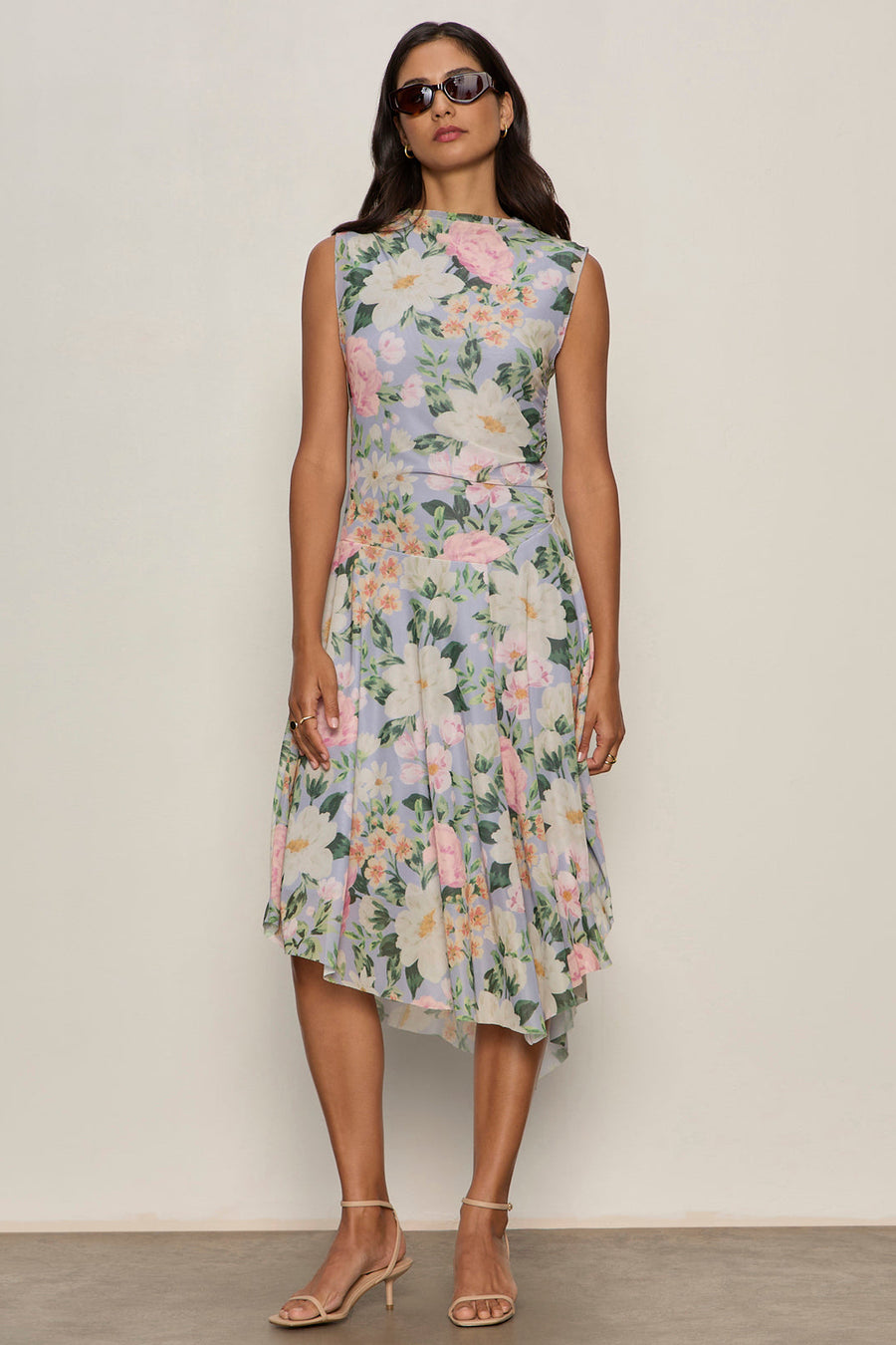 a woman wearing a floral print sleeveless midi asymmetrical dress 
