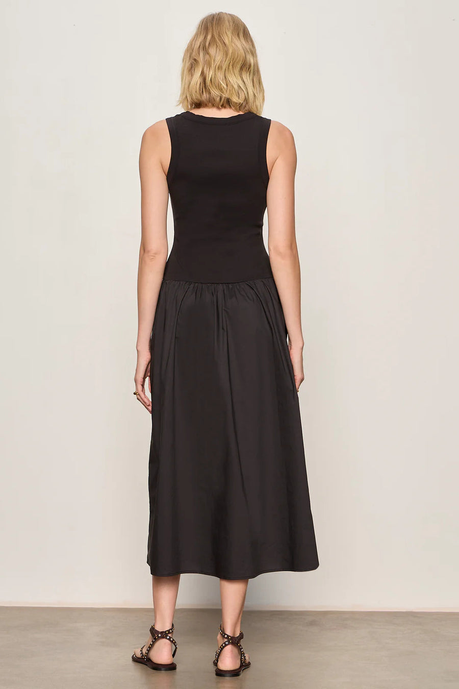 Woman wearing a black sleeveless knit midi dress with button up details