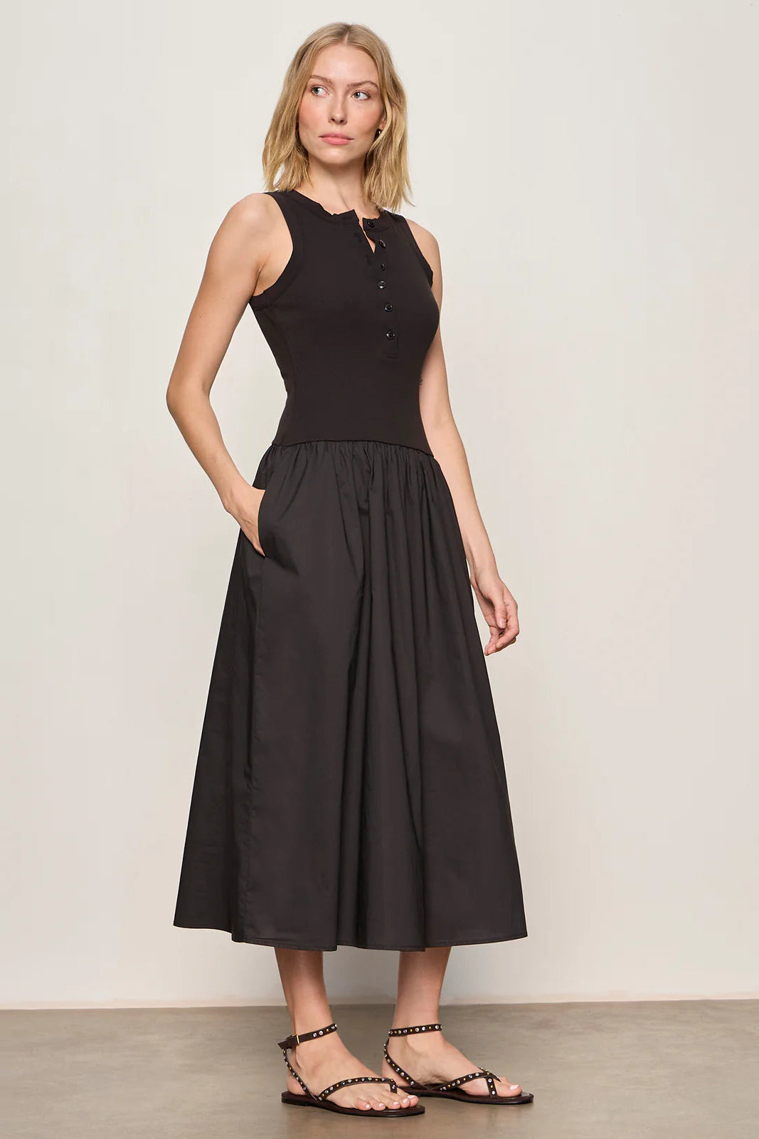 Woman wearing a black sleeveless knit midi dress with button up details