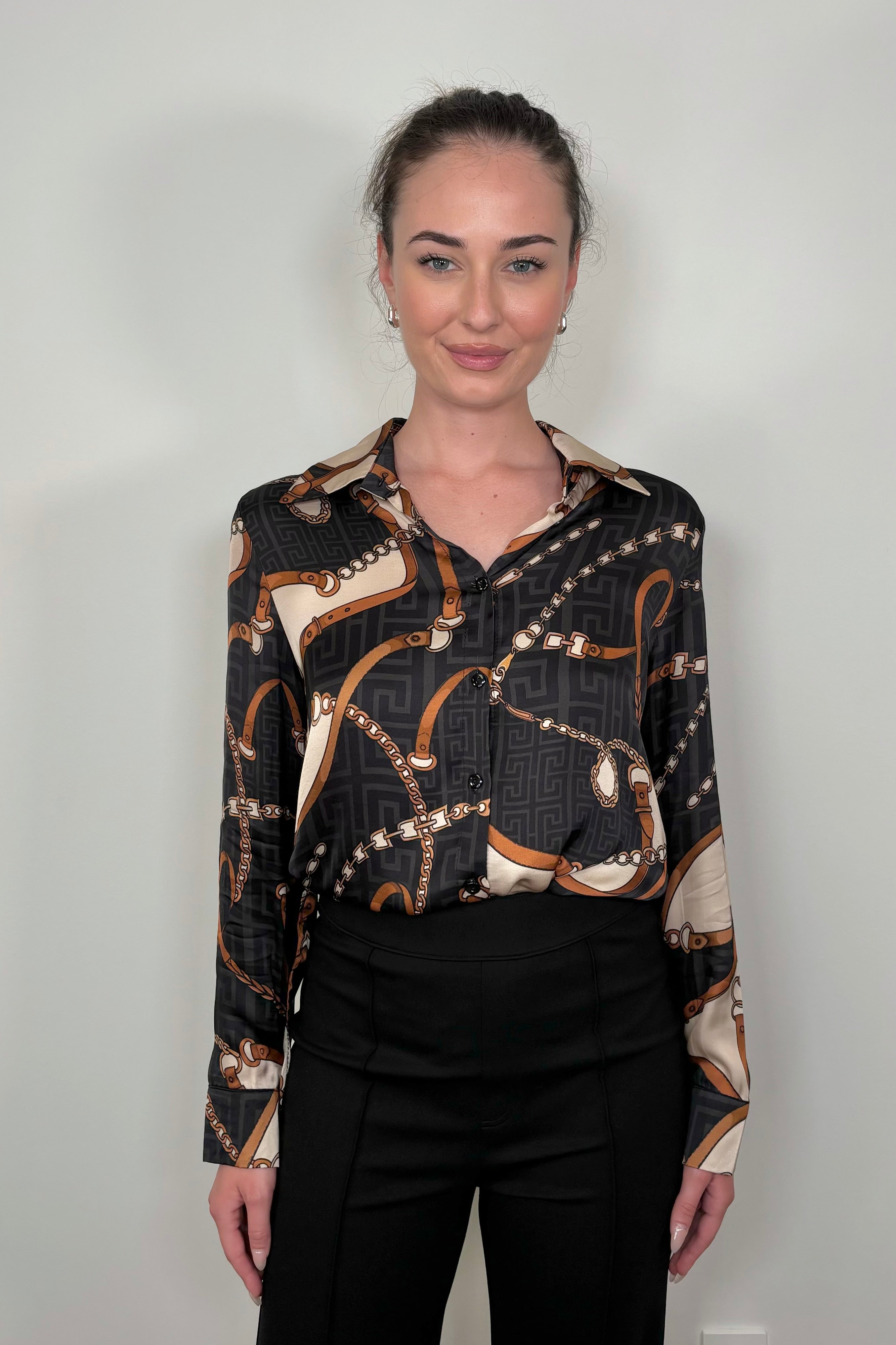 Front view of a woman wearing a printed button up shirt tucked in
