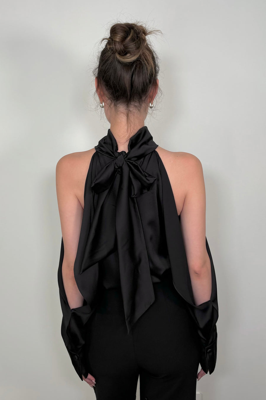 Back view of woman wearing a black satin off-shoulder halter top 