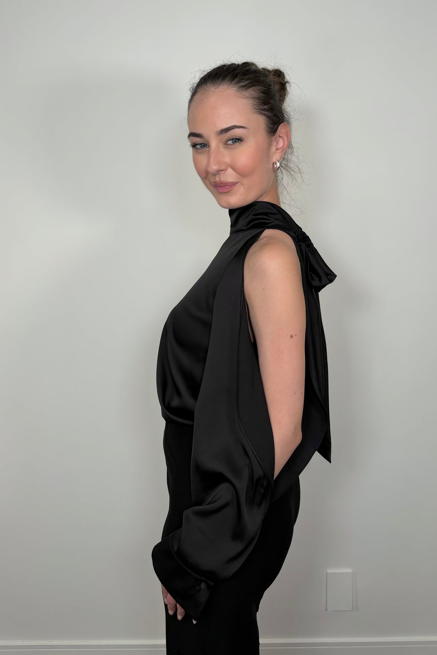 Side view of woman wearing a black satin off-shoulder halter top 