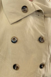 Woman wearing a beige trench coat with plaid cuffs