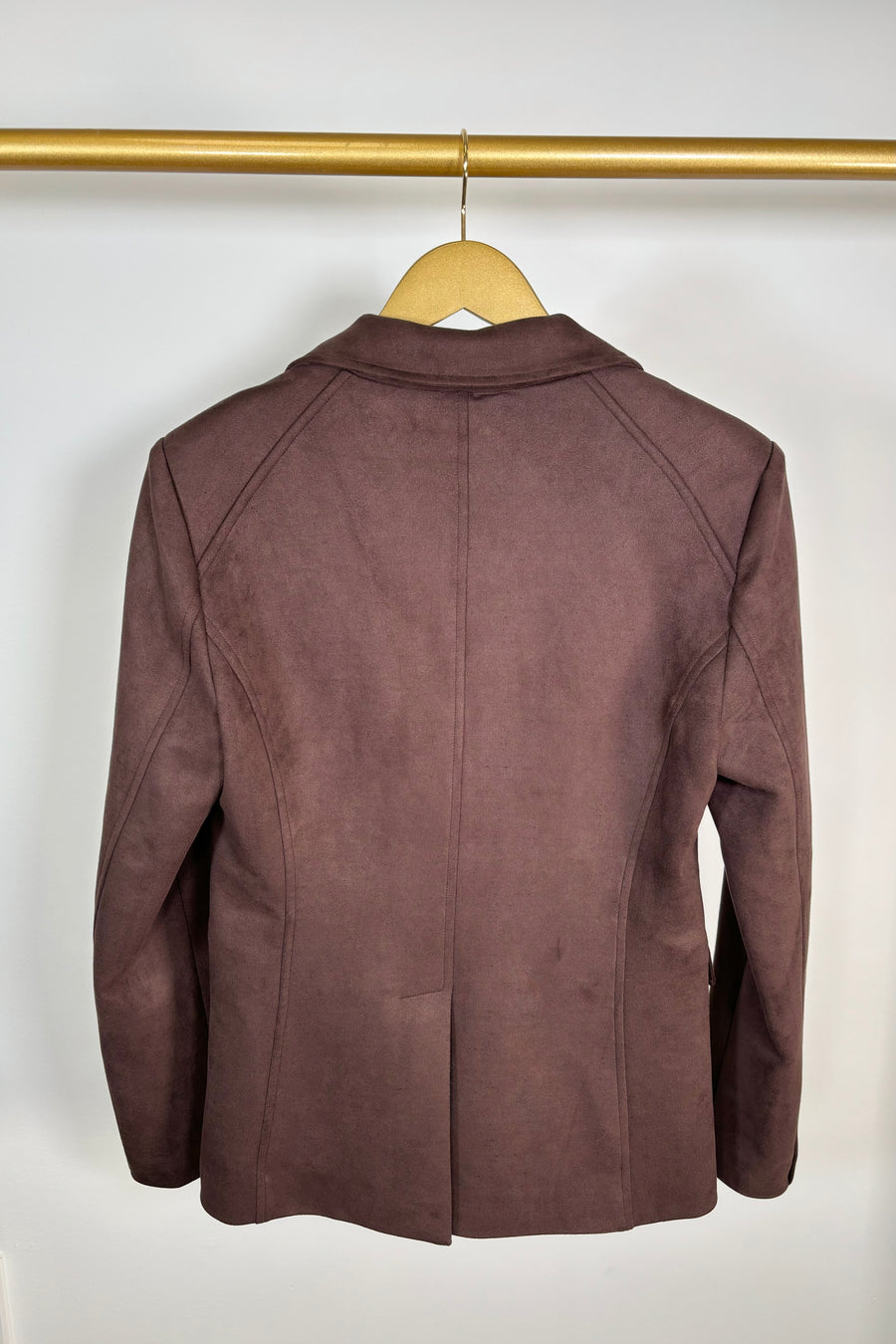 Back view of a brown jacket on a hanger against a white background