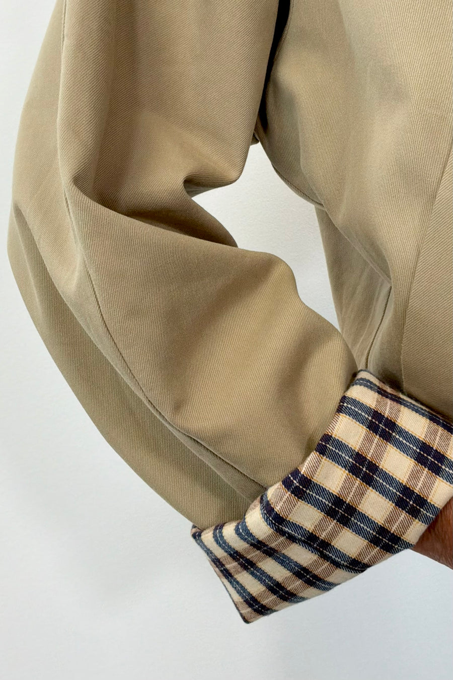 Woman wearing a beige trench coat with plaid cuffs