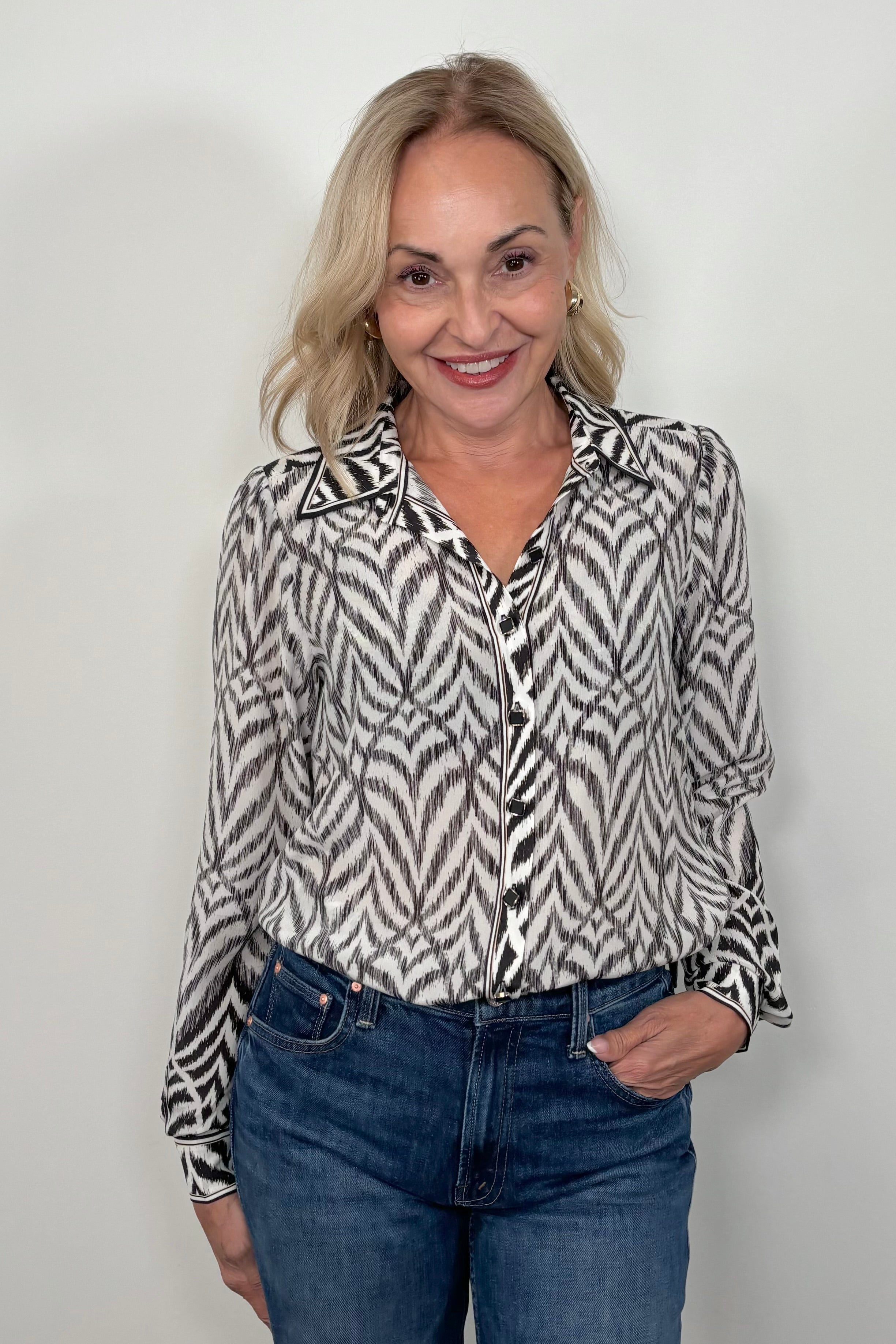 Front view of woman wearing a tucked in Button up blouse with zig zag black stipes