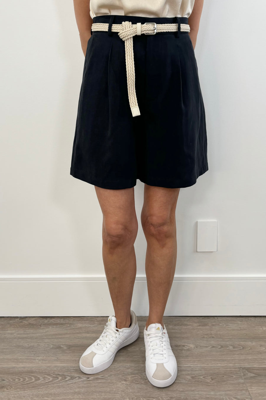 Woman wearing navy blue shorts with white braided belt detail