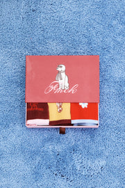 Three pairs of crew socks in red, mustard yellow, and dark brown. Each sock features a different embroidered character or graphic on the front.