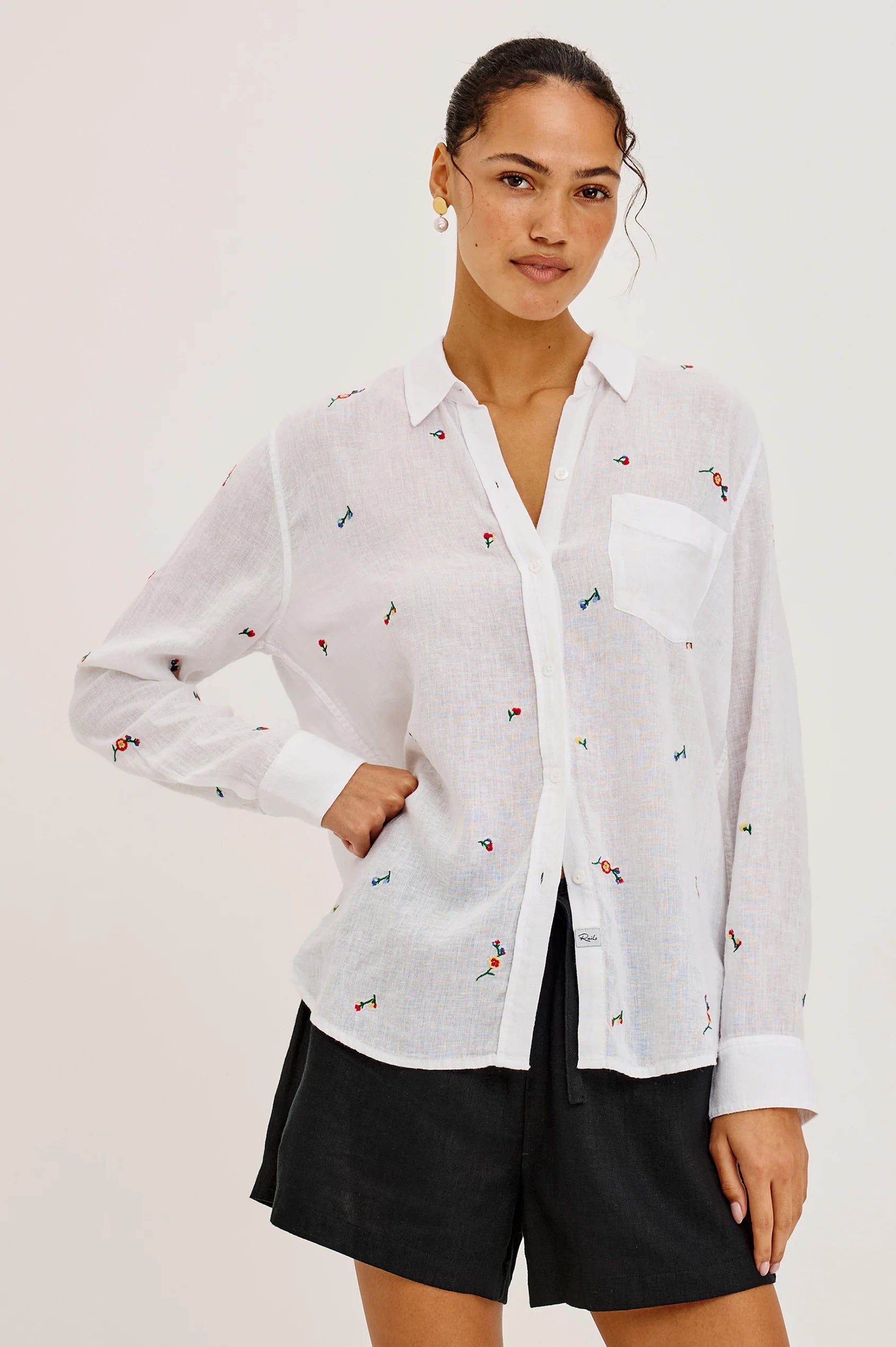 Woman wearing a white button up blouse with flower embroidery 