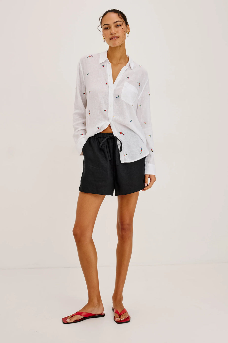 Woman wearing a white button up blouse with flower embroidery 