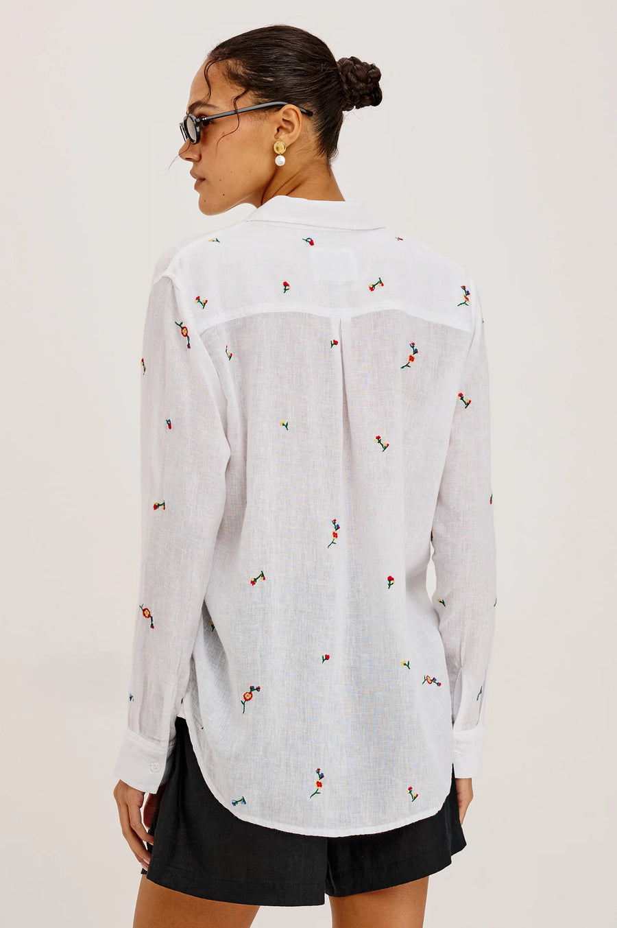 Woman wearing a white button up blouse with flower embroidery 