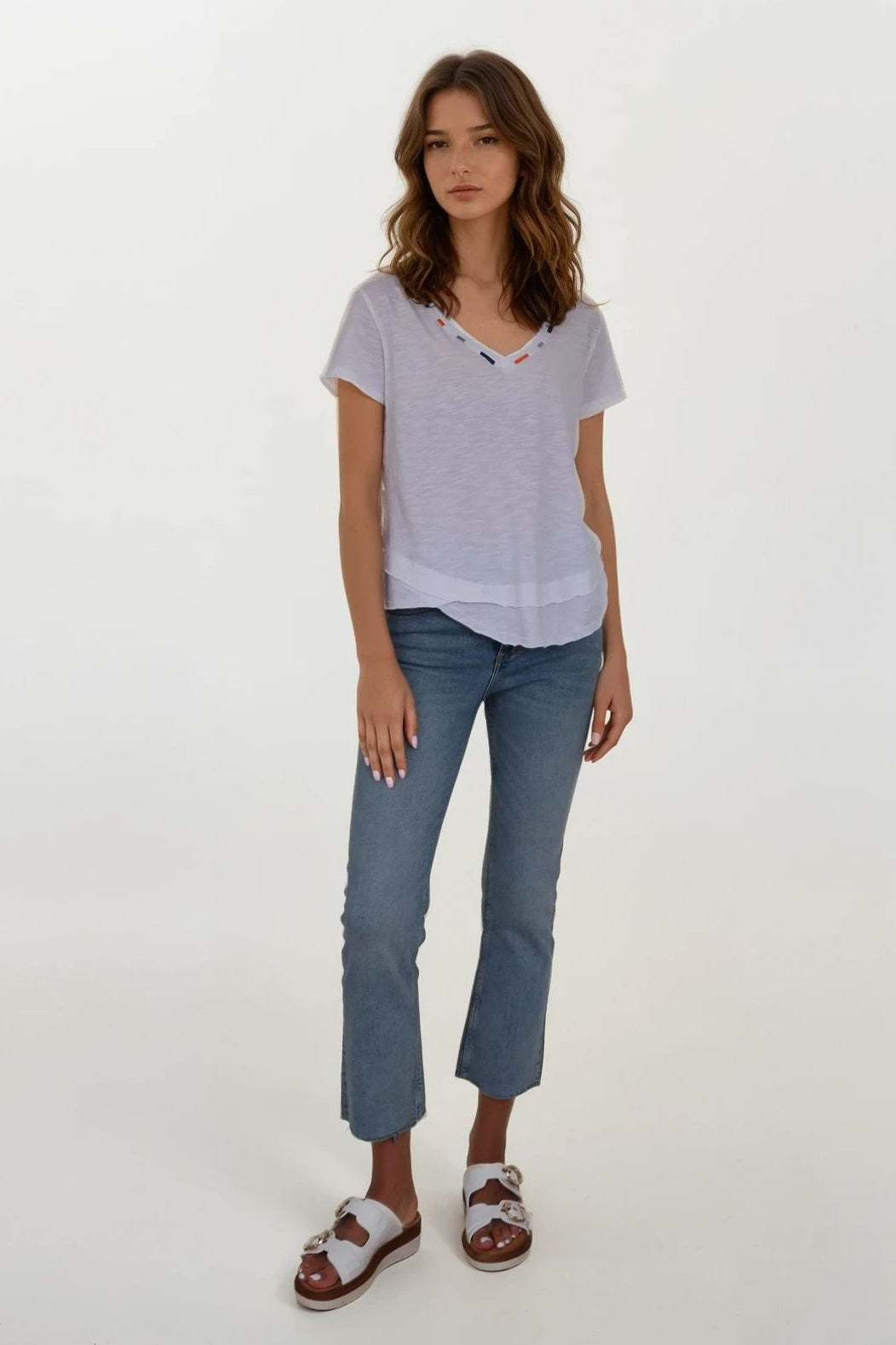 woman wearing a white vneck tee shirt with details on neckline