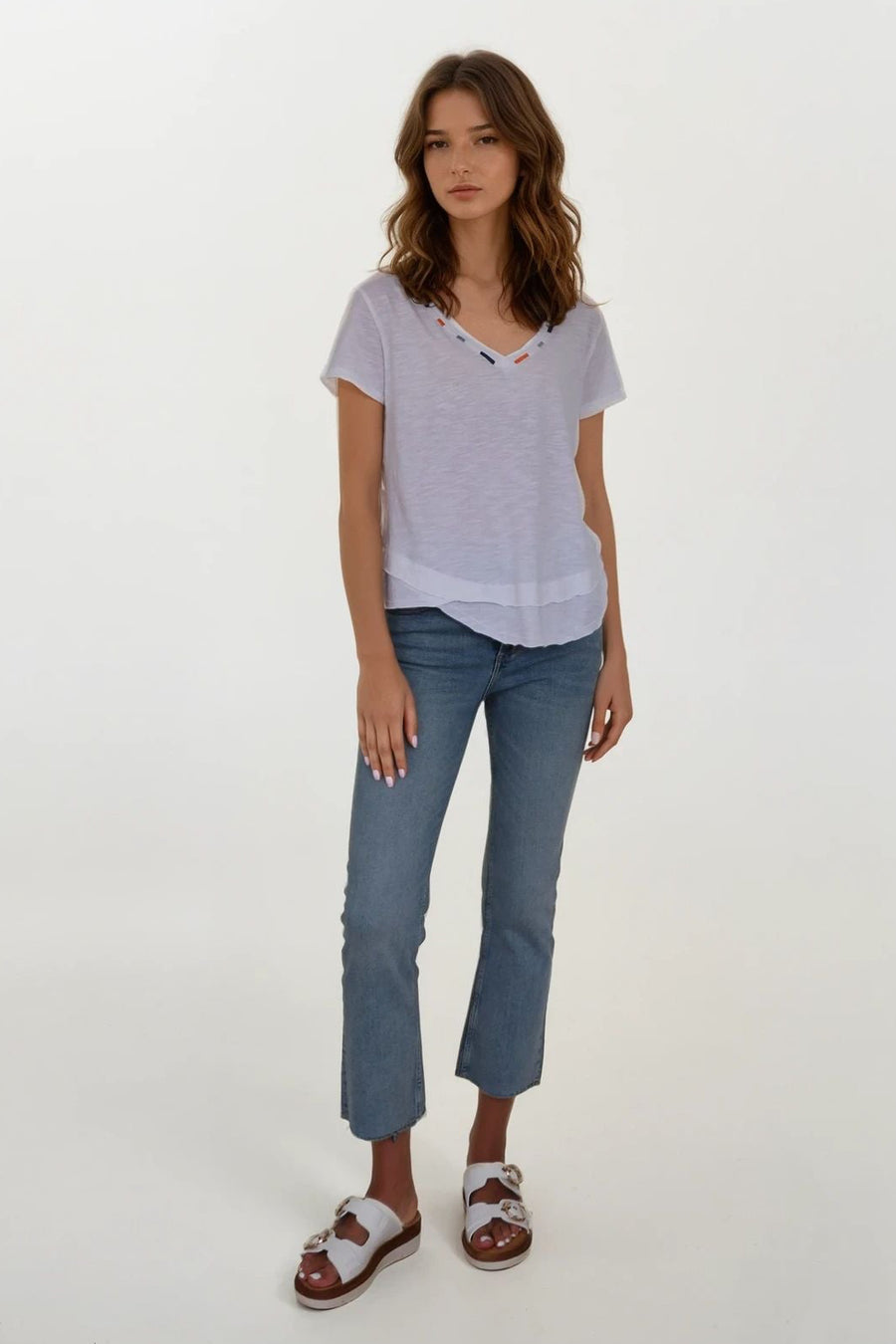 woman wearing a white vneck tee shirt with details on neckline
