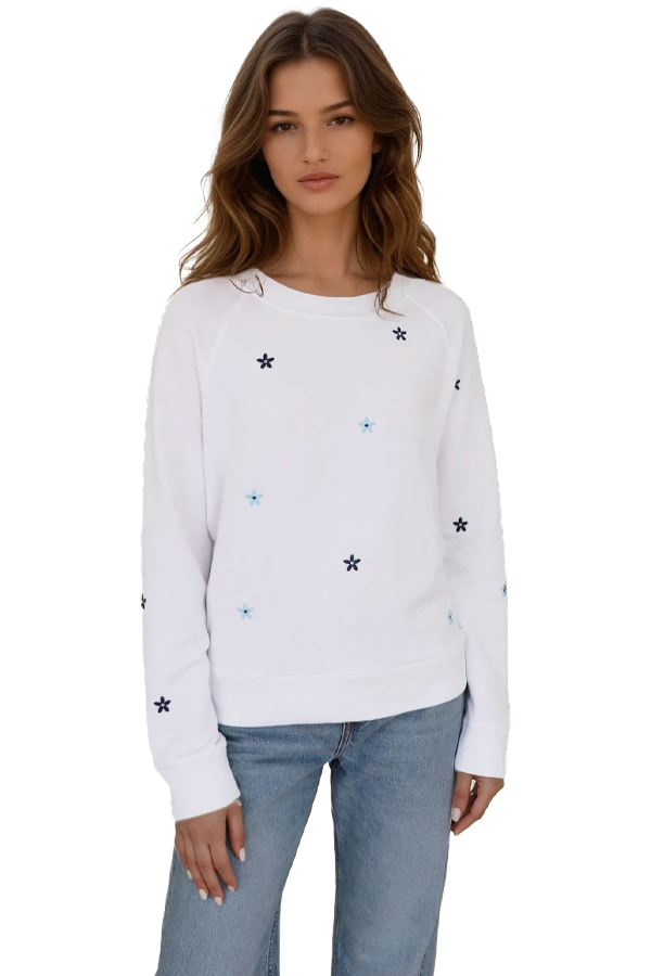 Woman wearing a white long-sleeve crewneck sweatshirt with embroidered floral accents, front view